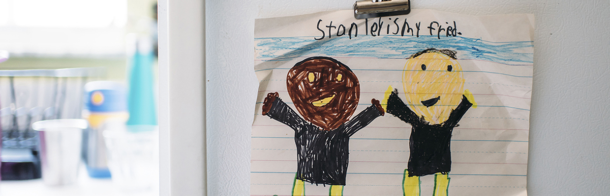 Child's drawing showing two people with different skin color smiling and raising their hands
